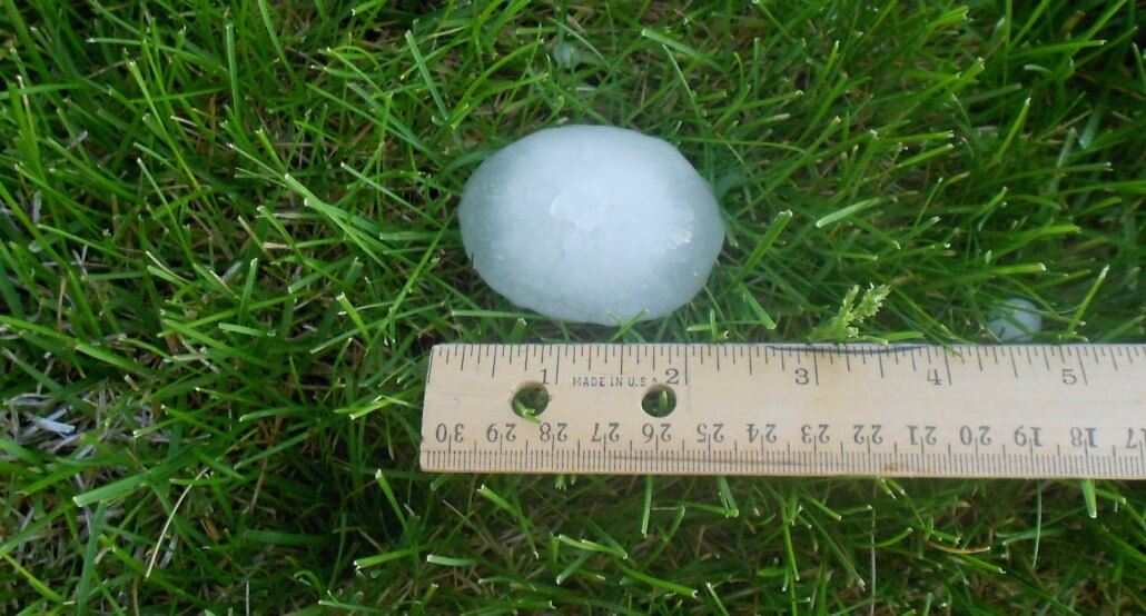 large ball of hail next to a ruler measuring over 2 inches
